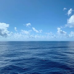 Fototapeta premium Vast ocean under a clear blue sky with scattered clouds