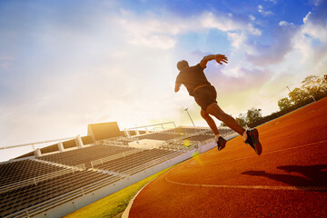 Silhouette of fit young man running sprinting at the racetrack. Fit runner fitness runner during outdoor workout at racetrack