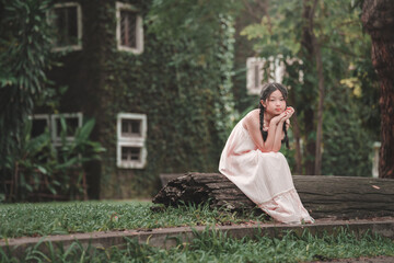 Fototapeta premium Contemplative teenage girl sitting on log serene nature outdoor portrait peaceful setting