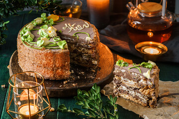 Kiev cake with cream, nuts , chocolate on wooden background with flowers and tea. Holiday dessert, sweets and pastry, close up