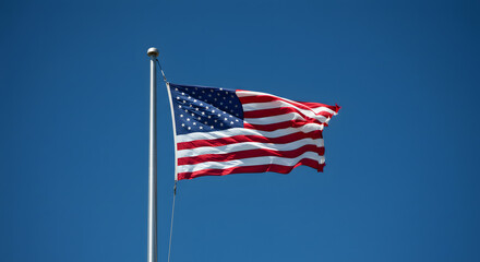Naklejka premium American Flag Waving Against a Clear Blue Sky
