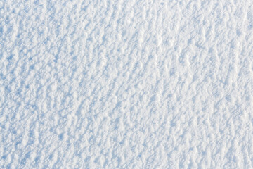 Natural snow texture. The surface of an icy snow crust. Snowy ground. Winter background with snow patterns. Perfect for Christmas and New Year design. Closeup top view.