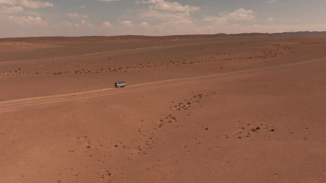 Aerial drone views of a UAZ van Cruising through the vast Gobi Desert of Mongolia at daylight in an extreme adventure