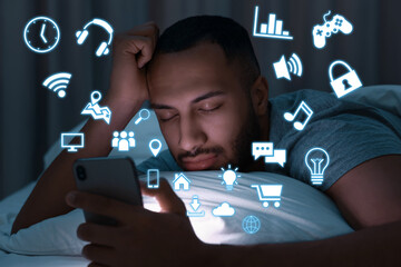 Internet addicted man sleeping while holding mobile phone at night. Different icons flying out of device