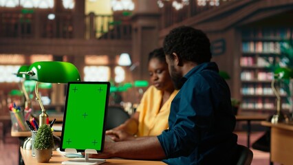 African american team studying for exams next to chroma key display, reading important information from copy books. Young university students use learning tools from database. Camera B.
