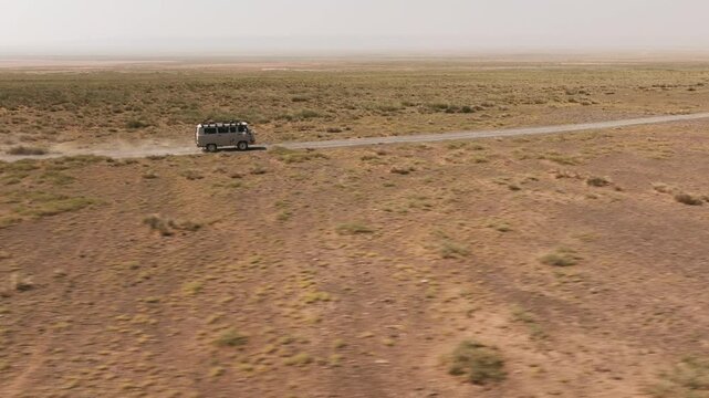 Aerial drone views of a UAZ van Cruising through the vast Gobi Desert of Mongolia at daylight in an extreme adventure