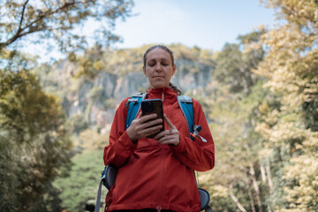 Hikers or explorers happy on journey carrying backpack, trekking poles looks into smartphone observing and possibly guide trekking and trail exploration holiday ecotourism concept.
