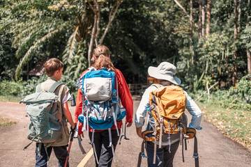 Hikers or explorers family on journey carrying backpack, trekking poles  looks into the distance observing guide trekking and trail exploration holiday ecotourism concept