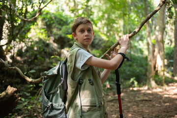 Young boy outdoor hiking backpack and walking stick looks into the distance observing and possibly guide trekking and trail exploration holiday ecotourism concept.