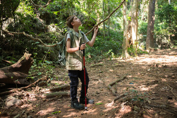 Young boy outdoor hiking backpack and walking stick looks into the distance observing and possibly guide trekking and trail exploration holiday ecotourism concept.