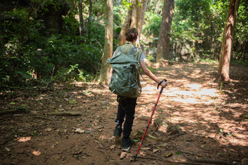 Young boy outdoor hiking backpack and walking stick looks into the distance observing and possibly guide trekking and trail exploration holiday ecotourism concept.