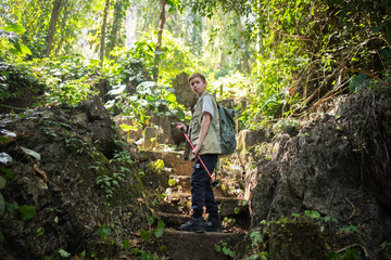 Young boy outdoor hiking backpack and walking stick looks into the distance observing and possibly guide trekking and trail exploration holiday ecotourism concept.