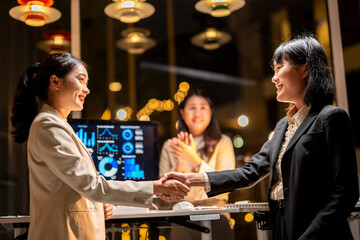 A woman shakes hands with another woman in a business setting