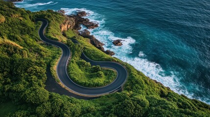 Winding Coastal Road on Lush Green Cliffside Above Blue Ocean Waters with Crashing Waves and Rocky Outcrops