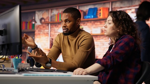 IT employees in startup office working at computer desks, testing and deploying programs and systems. Programmer and developer checking code on desktop PCs, solving tasks in workspace, camera B