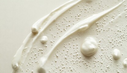 Off-white creamy substance with textured swirls and small bubbles, applied on a light background
