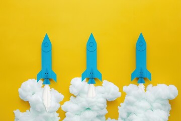 Three blue rockets launching against a bright yellow background.