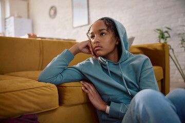 Sad African American teenage girl thinking of something at home.