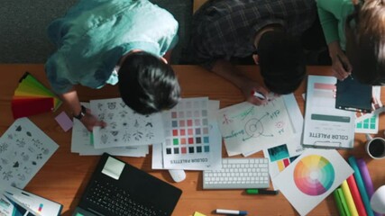 Top down aerial view of project manager looking at screen while designer writing idea. Smart business team explain idea of logo design while designer choose theme while looking at palette. Symposium. - Powered by Adobe
