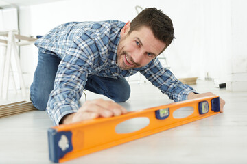 man using a spirit level to check new flooring