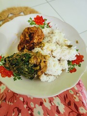 A meal of rice, vegetables, and protein on a plate.