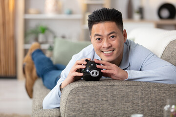 young asian man holding a piggy bank