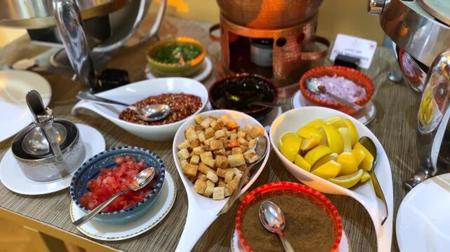 High-resolution footage of a vibrant condiment station featuring lemons, croutons, spices, chopped vegetables, and sauces&mdash;perfect for culinary, buffet, or hospitality visuals.