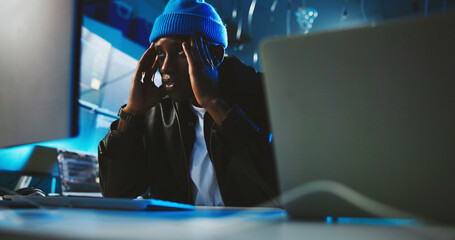 Night, hacker and man with stress, computer and risk of detection, thinking and worried for failure. Contemplating, programmer and black person with anxiety for ransomware, fraud and spy in office