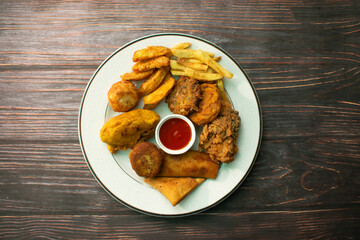 Chicken Samosa, Chicken Roll , shami Kebab, Egg Chop, French Fry, Potato Wedges, Vegetable Pakora, Vegetable Roll, Alu Chop, Chicken Ball served in plate isolated top view of bangladeshi food