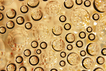 Abstract close-up of clear glass bubbles or spheres embedded in a golden-hued surface, creating a textured and reflective pattern. Ideal for backgrounds, concepts, or art.