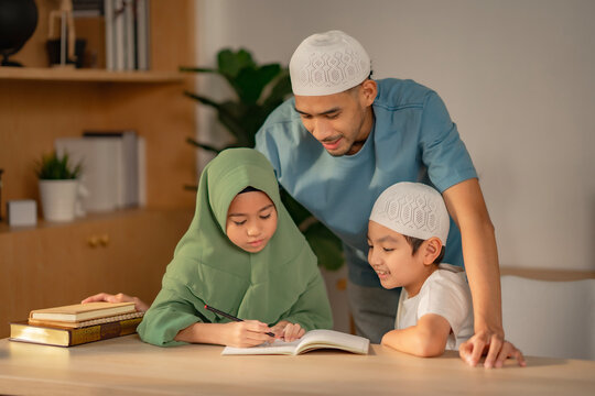 At home, a Muslim dad guides his children through their homework. The family shares a joyful and productive study moment together...