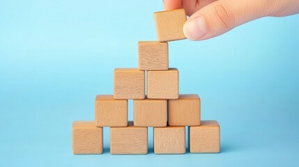 Hand placing wooden block on a pyramid structure