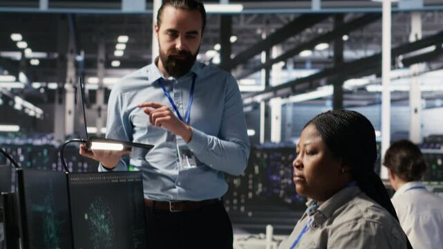 Annoyed data center employee making rude hand gesture toward colleague during workplace disagreement. Upset woman in server hub being dismissive to coworker during dispute, camera A