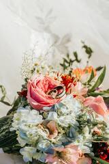 Close-up of wedding rings on a colorful sunny bouquet