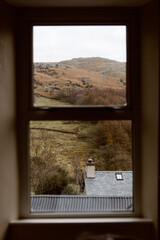 Hills and rooftops seen through window on an overcast day in Ulpha
