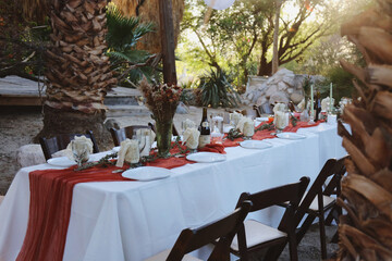 Rustic outdoor banquet table with red accents and candles.