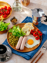 English breakfast with eggs, sausages and green peas