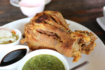 Golden deep fried pork knuckle on white plate and dipping sauce in a restaurant.Homemade crispy