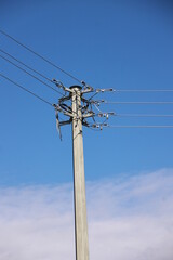 Tall pole with wires on it is standing in a blue sky