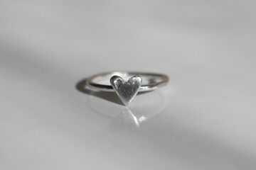 Tiny silver ring in the shape of a heart on a white background. Handmade jewelry.