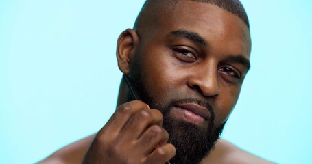 Face, black man and styling beard with beauty for wellness, haircare and cosmetics on blue background. Comb facial hair, self care and healthy glow with portrait on studio, dermatology and grooming