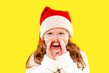 Excited child wearing a festive hat and warm sweater celebrating the holiday season with joy in front of a bright yellow background