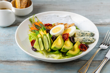 Healthy salad bowl with grilled chicken, avocado, egg, and blue cheese