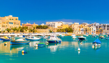 Fototapeta premium Beautiful cityscape of Birzebbuga with fishing boats lying on the water, Malta