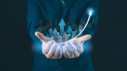 A person in a suit holds virtual graphics of upward arrows and a rising curve, symbolizing business growth and financial success.
