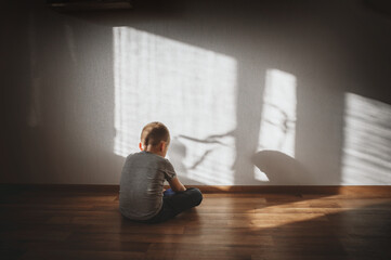 Little boy lonely depressed standing with back sitting on floor sad autism. autism spectrum...