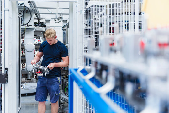 Technician working with industrial robots in a production hall