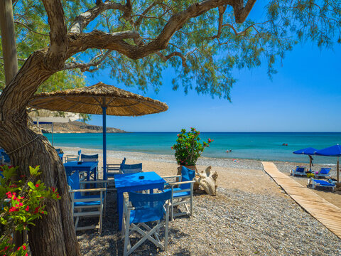 Parasols and tables with chairs set up on a quiet resort beach (Kato Zakros beach, Crete, Greece)