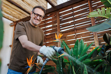 Man gardening on a rooftop terrace with tropical plants