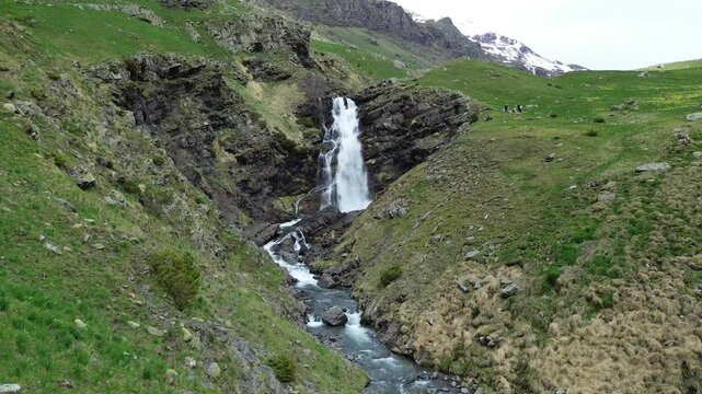 A waterfall cascading down a lush green valley in arag&oacute;n, spain, aerial view